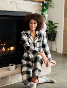 Black and white flannel Pj's being modeled next to a fireplace.