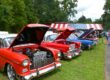 Photograph of the VFW's Freedom Car Show with two red and one blue cars in front of an American Flag roof.