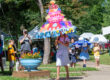 Photograph of a female child carrying a decorated umbrella to look like a cake celebrating the 150th birthday of Rain Day in Waynesburg, Pennsylvania.