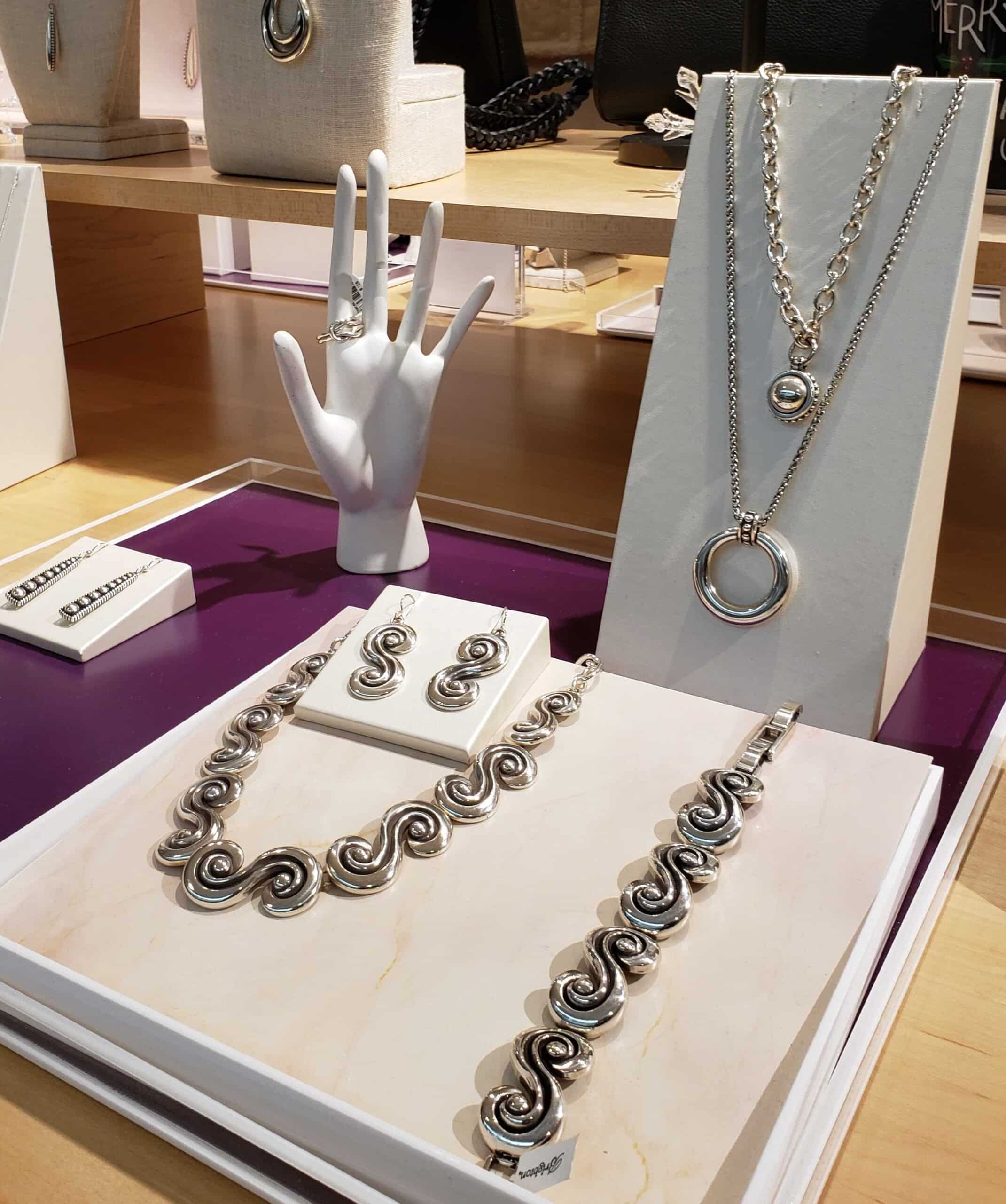 Photograph of silver jewelry at Fashion Shoppe. Set includes a necklace, bracelet and earrings in a coiled design.