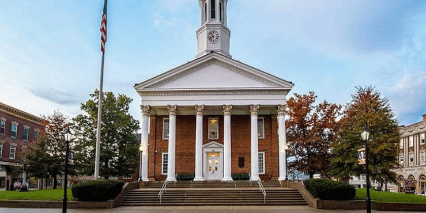 Downtown Waynesburg by Ben McMillen Historic brick courthouse with white columns and a clock tower in a small-town downtown square, surrounded by red-brick buildings and autumn trees.