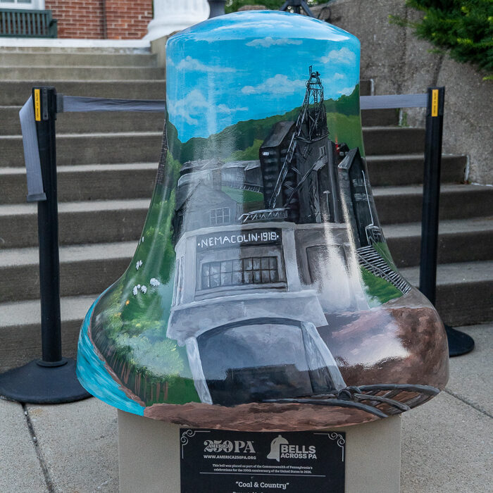 Painted bell sculpture featuring the historic Nemacolin coal mine and surrounding Greene County landscape, displayed as part of the Bells Across PA public art exhibit.
